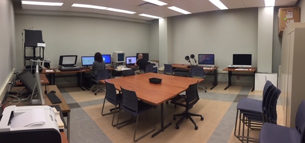 A room with tables in the middle with computers creating an entire border around the room.
